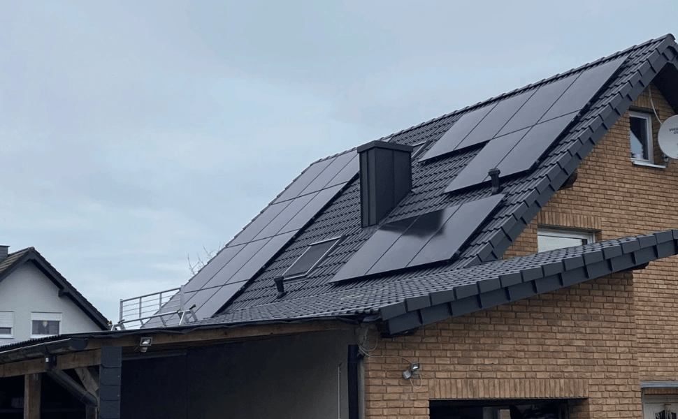 Solarmodule auf dem Dach eines Hauses, bewölkter Himmel im Hintergrund